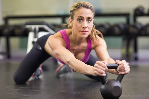 Ernstige vrouw opheffing waterkoker bell in gym — Stockfoto