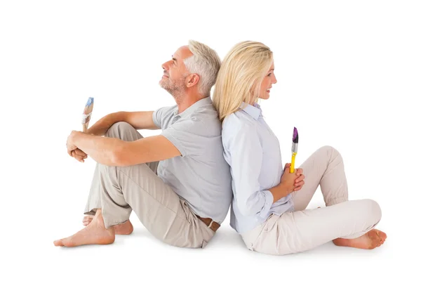 Lyckliga paret sitter och håller penslar — Stockfoto
