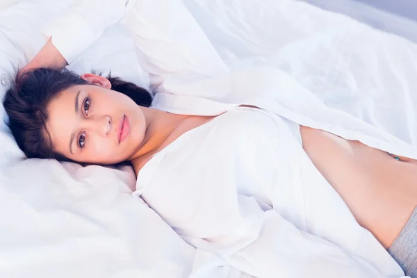 Sexy brunette smiling at camera on bed — Stock Photo, Image