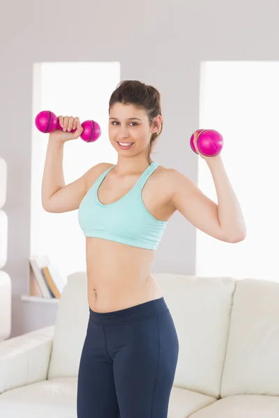 Fit Brünette mit Hanteln, die in die Kamera lächeln — Stockfoto