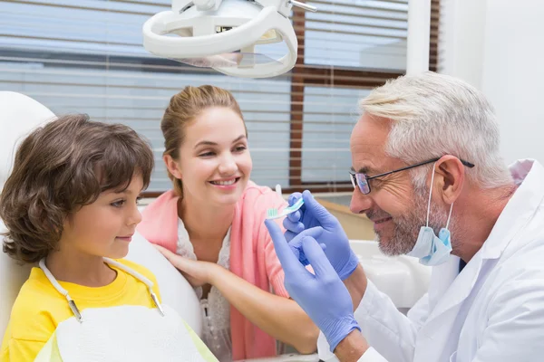 Kinderzahnärztin zeigt Jungen eine Zahnbürste — Stockfoto