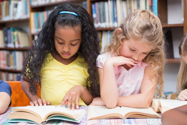 Alumnos que leen libros en la biblioteca — Foto de Stock