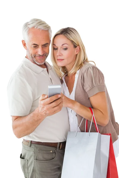 Happy couple holding shopping bags and smartphone — Stock Photo, Image