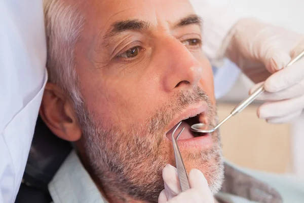 Dentista examinando los dientes de un paciente — Foto de Stock