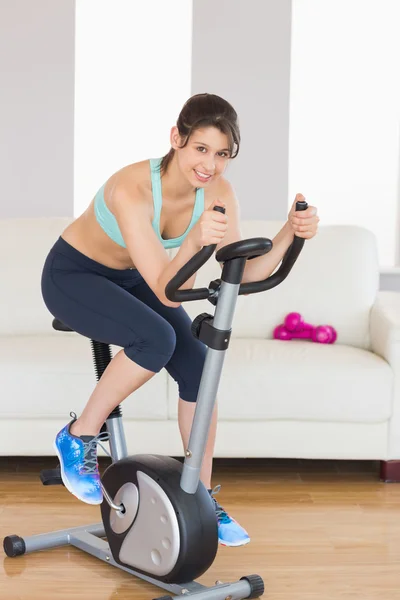 Passa brunett som träna på motionscykel — Stockfoto