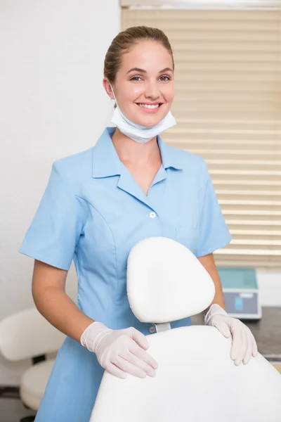 Diş asistanı kamera sandalye yanında gülümseyen — Stok fotoğraf