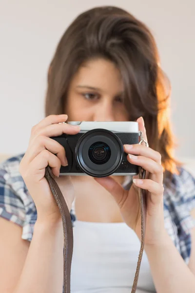 Pretty brunette looking at retro camera on couch — Stock Photo, Image