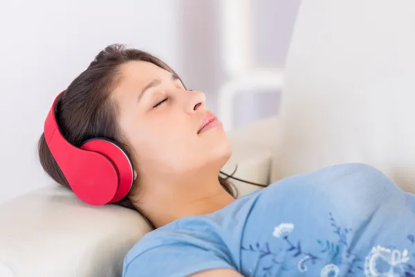 Mooie brunette luisteren naar muziek op de Bank — Stockfoto