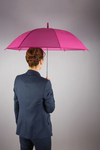 Businesswoman in suit holding pink umbrella — Stock Photo, Image