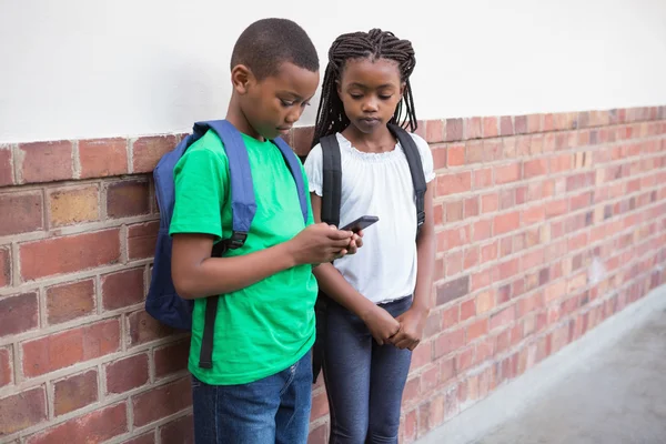 Pupils looking at smartphone in corridor — Stock Photo, Image