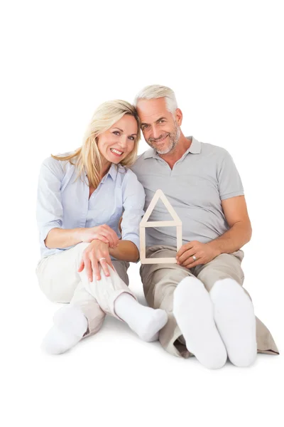 Glückliches Paar sitzt und Häuserumriss hält — Stockfoto