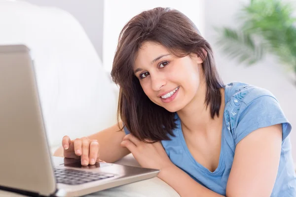 Pretty brunette using laptop on the couch — Stock Photo, Image