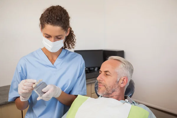 Dentist showing patient model of teeth — Stock Photo, Image