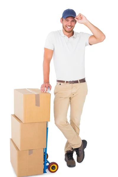 Happy delivery man leaning on trolley of boxes — Stock Photo, Image