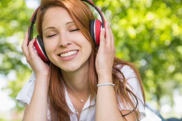 Redhead luisteren naar muziek in het park — Stockfoto