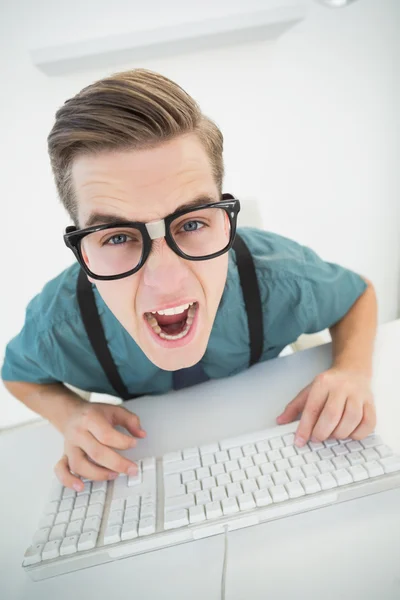 Casual angry businessman typing at his desk — Stock Photo, Image
