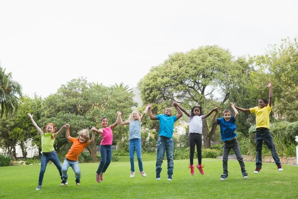 Pupils jumping on the grass outside — Stock Photo, Image