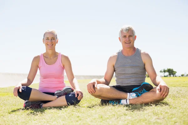 Ouder paar in lotus pose op het gras zitten passen — Stockfoto