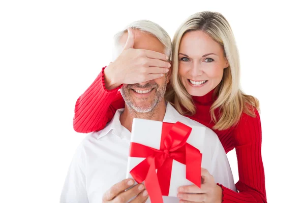 Mujer sonriente cubriendo los ojos de los socios y sosteniendo regalo — Foto de Stock