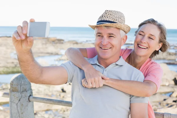 Lyckliga casual paret tar en selfie vid kusten — Stockfoto