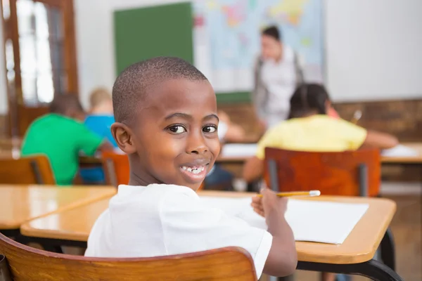 Leerling glimlachen achter zijn Bureau in klas — Stockfoto