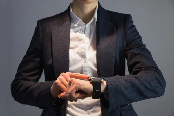 Businesswoman in suit pointing to watch — Stock Photo, Image