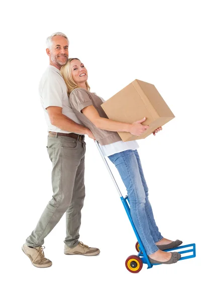 Happy couple having fun with trolley and moving box — Stock Photo, Image