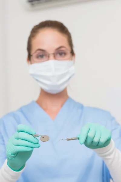 Dentist in blue scrubs holding tools — Stock Photo, Image