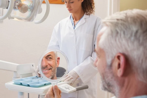 Paciente admirando una nueva sonrisa en el espejo — Foto de Stock