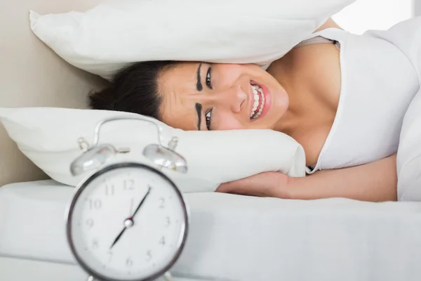 Mujer cubriendo orejas con almohadas en la cama —  Fotos de Stock