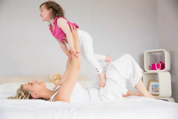 Mujer joven jugando con su hija en la cama —  Fotos de Stock