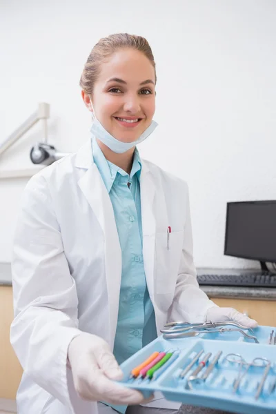 Dentista sentado con bandeja de herramientas sonriendo a la cámara — Foto de Stock