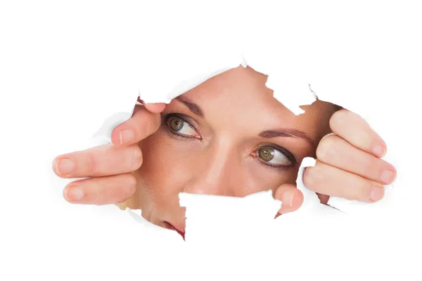 Woman looking through torn paper — Stock Photo, Image