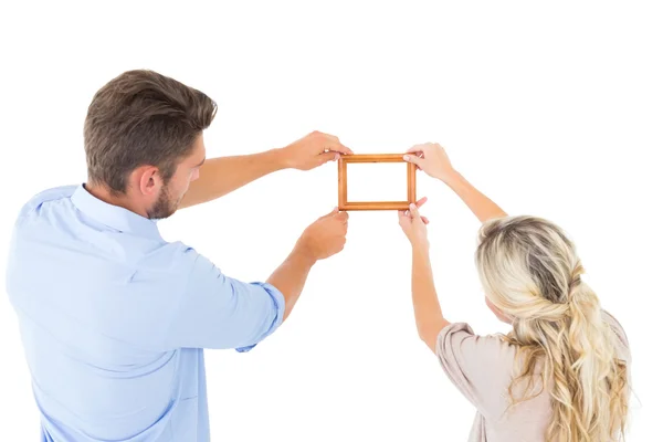 Attractive young couple hanging a frame — Stock Photo, Image