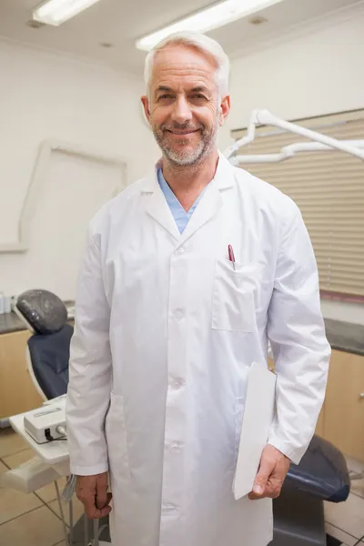 Стоматолог улыбается в камеру рядом со стулом — стоковое фото