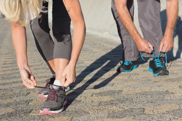 Couple tying their laces of running shoes — Stock Photo, Image