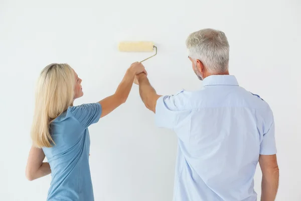 Parede de pintura casal feliz com rolo — Fotografia de Stock