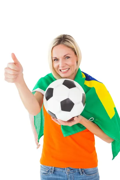 Футбольный болельщик держит мяч и носит бразильский флаг — стоковое фото