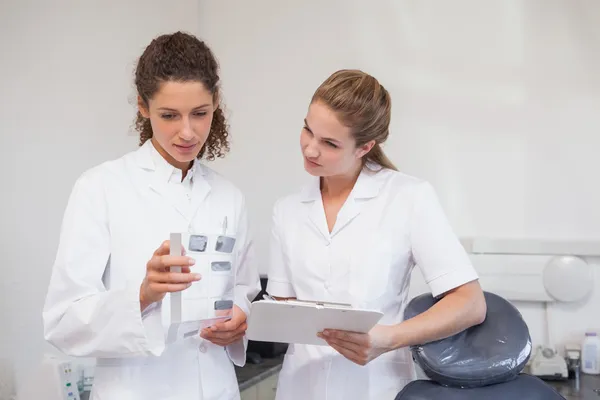 Dentista e assistente estudando raios-X — Fotografia de Stock