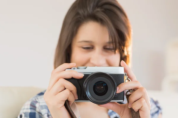 Pretty brunette looking at retro camera on couch — Stock Photo, Image