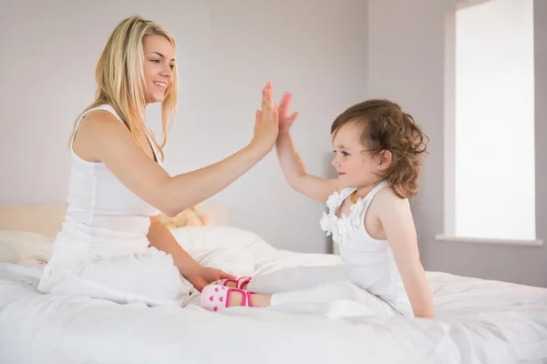 Moeder en dochter hoge fiving op bed — Stockfoto