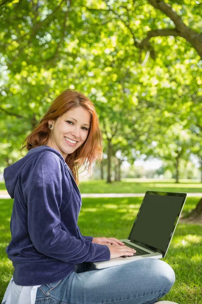 Ruiva relaxante no parque usando laptop — Fotografia de Stock