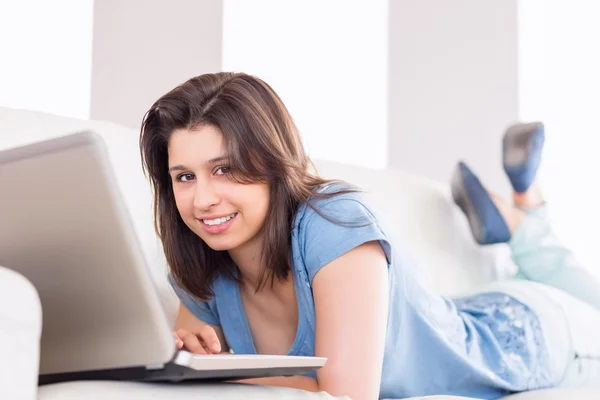 Pretty brunette using laptop on the couch — Stock Photo, Image