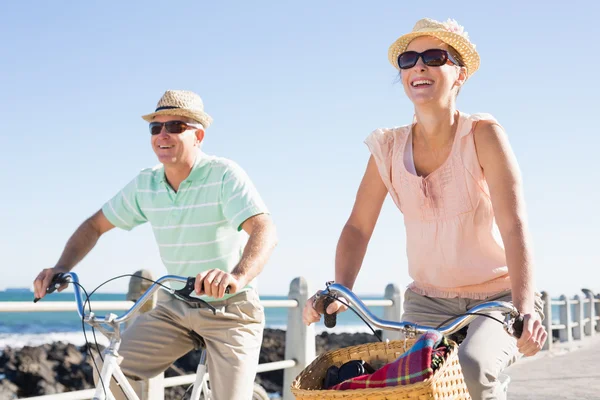 Glada casual par går för en cykeltur på piren — Stockfoto