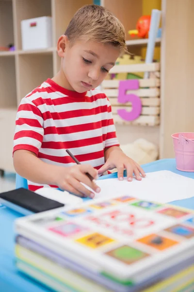 Симпатичный маленький мальчик рисует за столом — стоковое фото