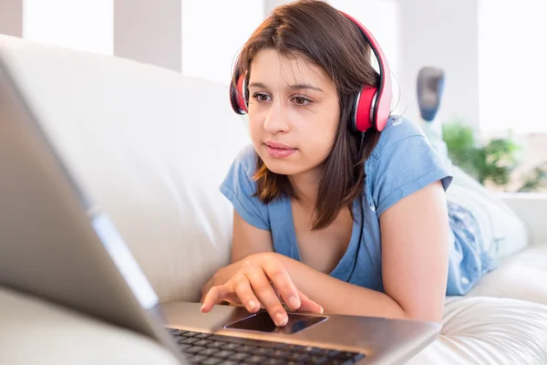 Chica usando el ordenador portátil y escuchando música — Foto de Stock