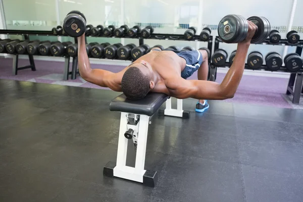 Spor salonunda dambıllarla egzersiz yapan bir adam. — Stok fotoğraf