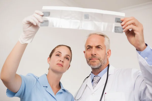 Dentista y asistente estudiando rayos X — Foto de Stock