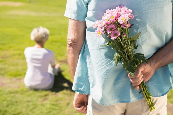 Homem sênior escondendo flores nas costas — Fotografia de Stock