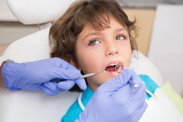 Odontólogo pediátrico examinando los dientes de un niño pequeño en los dentistas — Foto de Stock